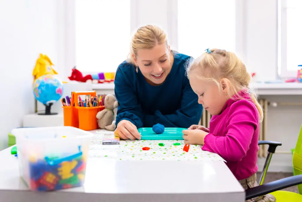An occupational therapy practitioner helps a young child with their task.