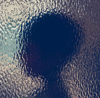 Blurred abstract silhouette of child head behind textured glass
