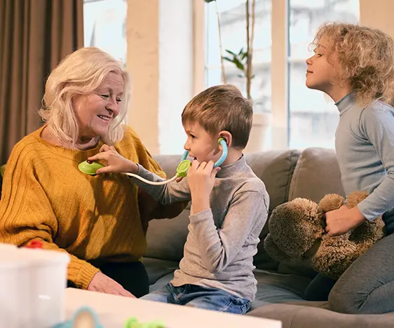 Boy uses stethoscope on grandmother while girl observes